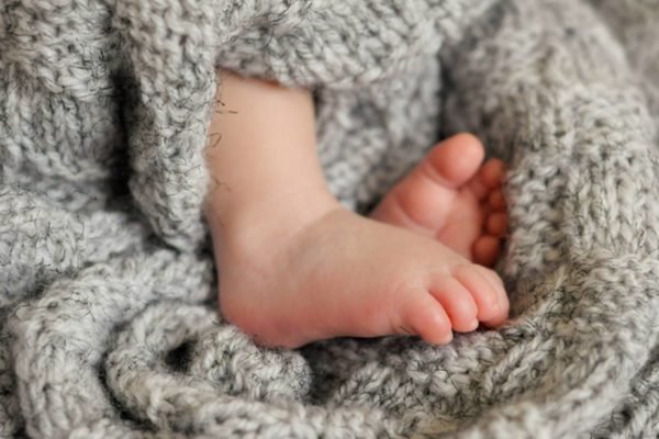 oscabecasdanoticia-getty Imagem colorida: pés de bebê envolvidos em cobertor - Metrópoles