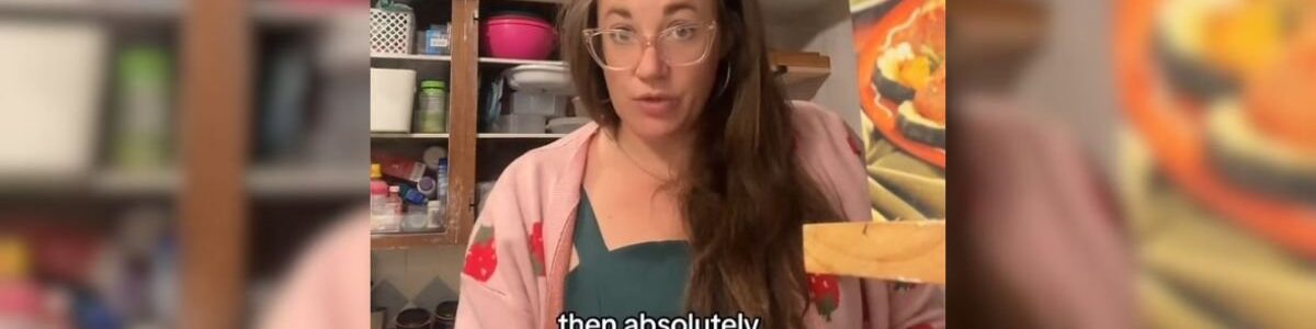 Imagem colorida de mulher olhando para a câmera enquanto cozinha - Metrópoles