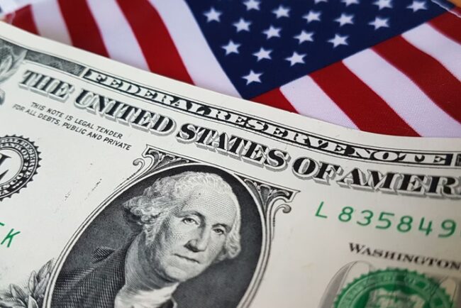 nota de dólar americano com bandeira dos EUA ao fundo