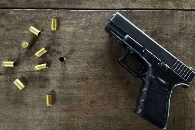 balas-vazias-e-uma-arma-na-mesa