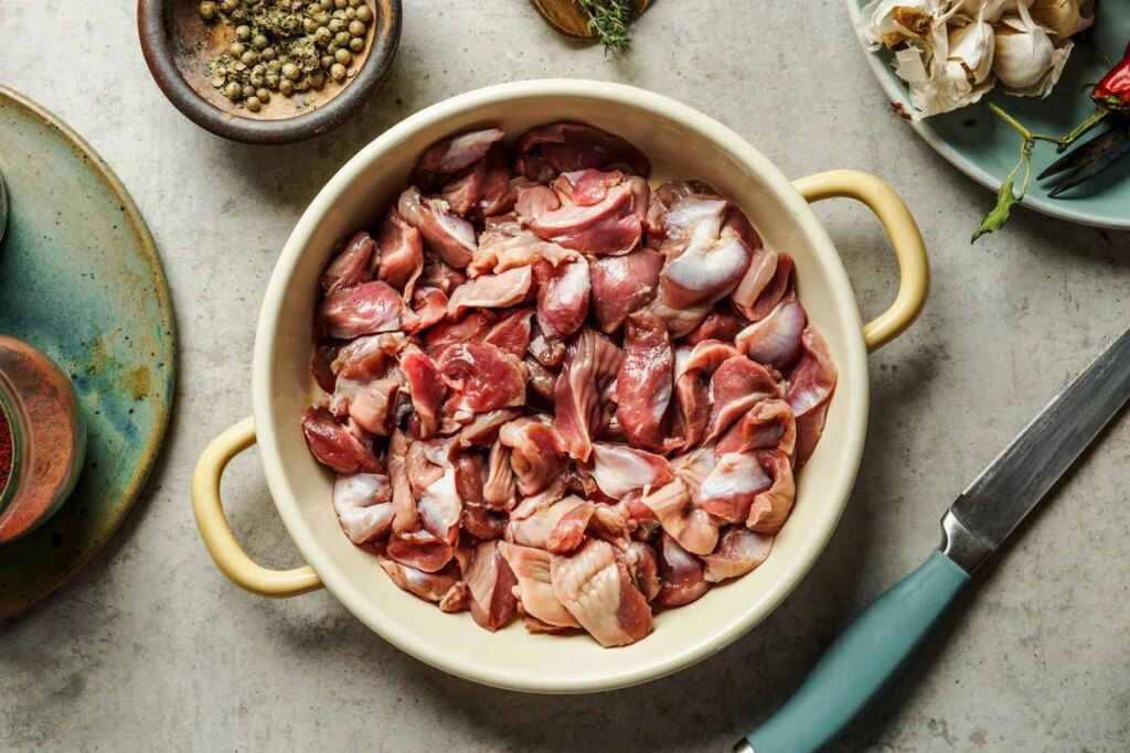 Moelas de frango cruas em uma panela sobre a mesa da cozinha. Preparação de alimentos. Vista superior. Metrópoles