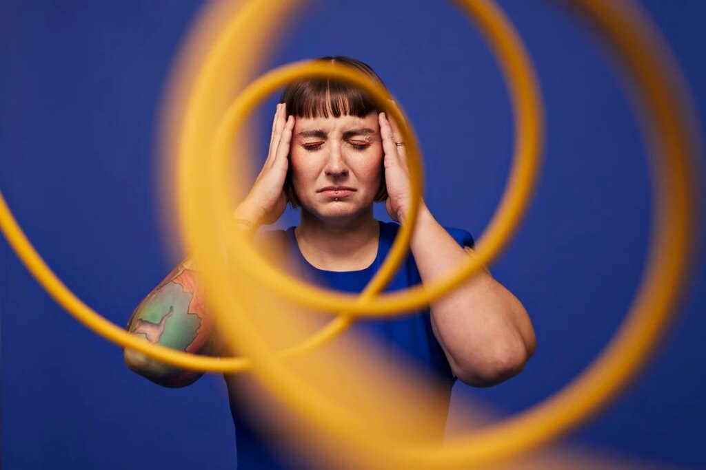 Imagem colorida mostra mulher branca de camisa azul e com tatuagens no braço com expressão confusa - Metrópoles
