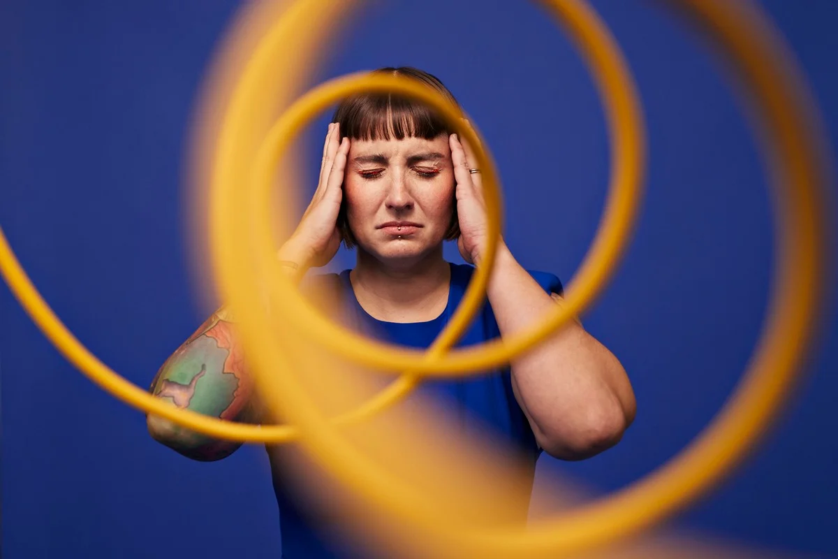 Imagem colorida mostra mulher branca de camisa azul e com tatuagens no braço com expressão confusa - Metrópoles