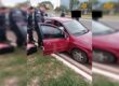 Imagem mostra policiais em frente a carro vermelho, que está com a porta aberta - Metrópoles