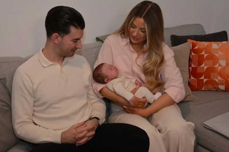 Foto colorida de familia com bebê recém-nascido no colo, resultad de transplante de útero em sucedido - Metrópoles.